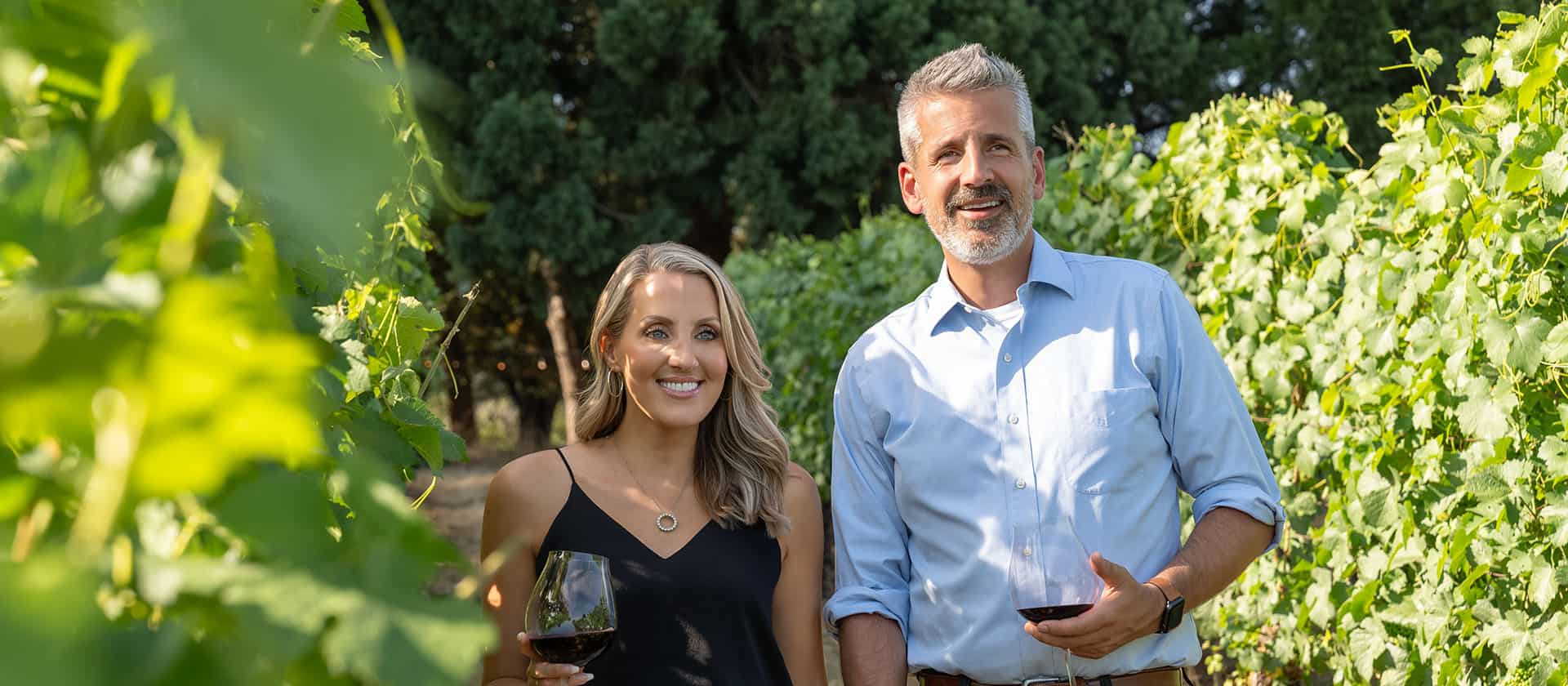 Couple Enjoys Walking In The Vineyards With Their Wine