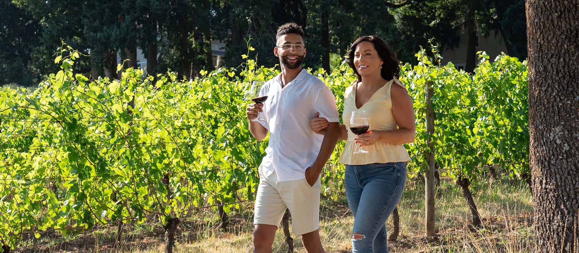 Couple Enjoys Walking In The Vineyards With Their Wine