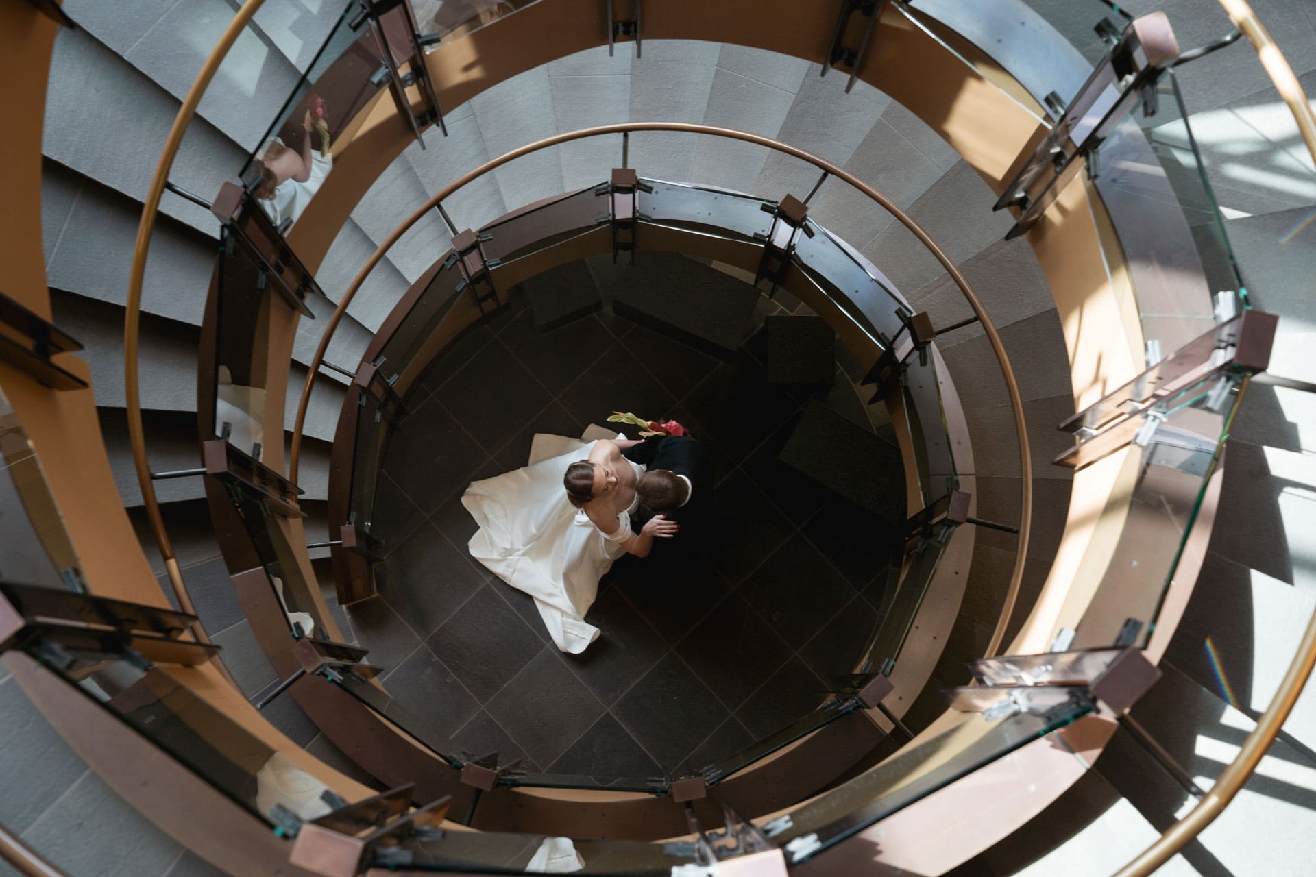 A bride and groom dancing at the base of the circular staircase.