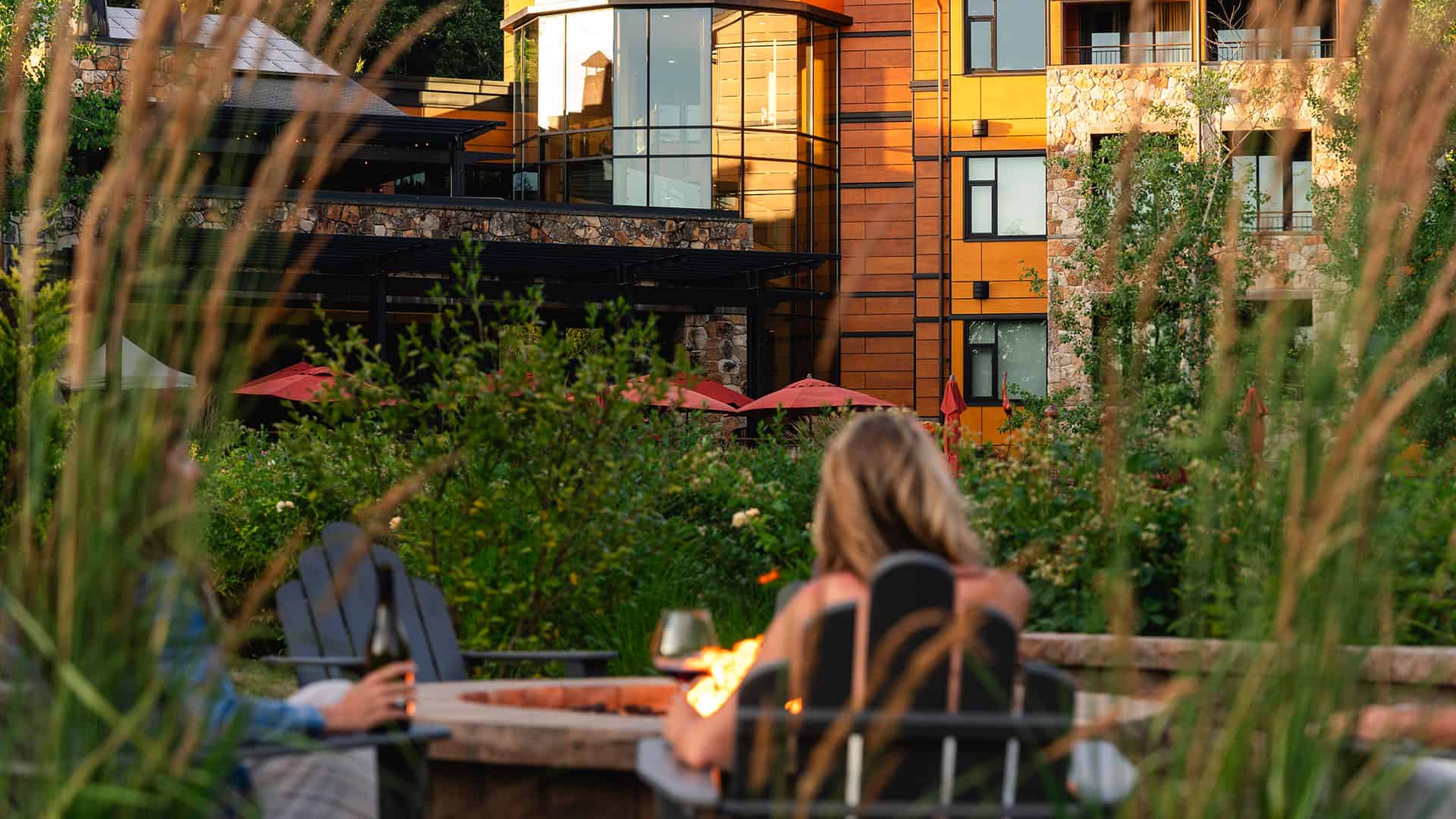 Two female guests drinking wine by the fire pit admiring the property view.