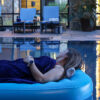 Female guest floating on an inflatable mattress in the swimming pool.