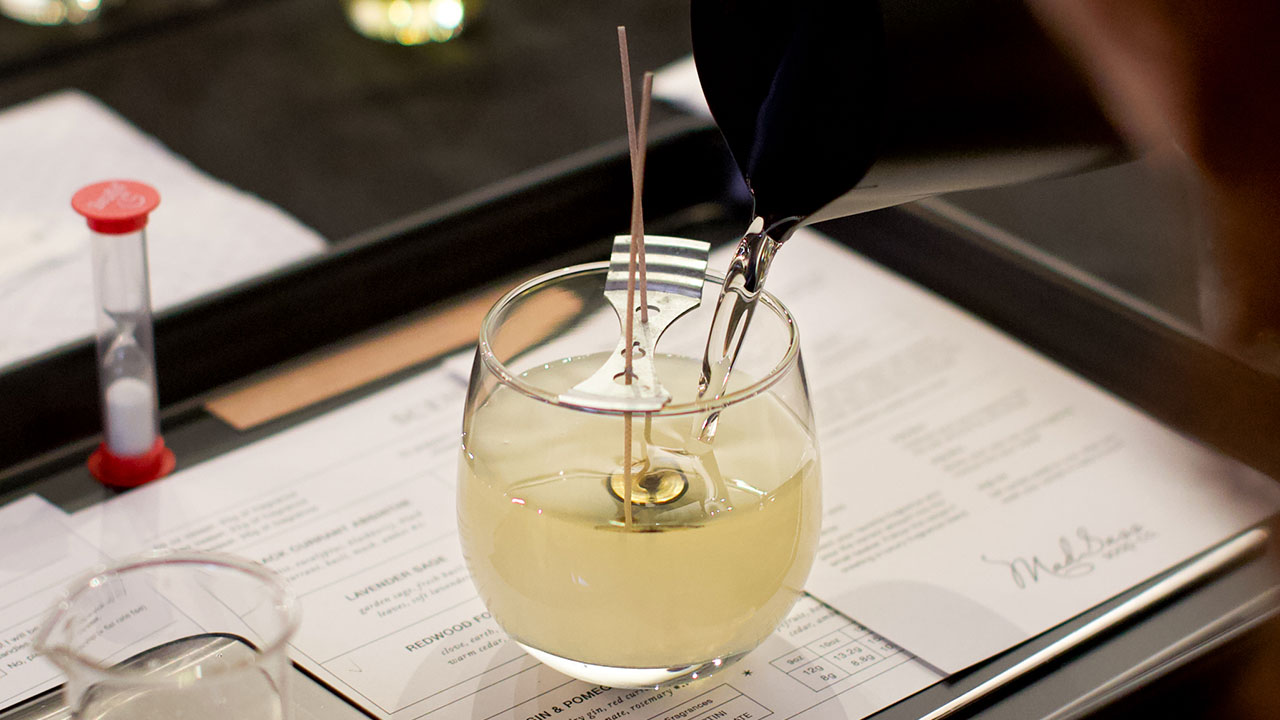 A guest pouring wax into a clear glass candle vessel.