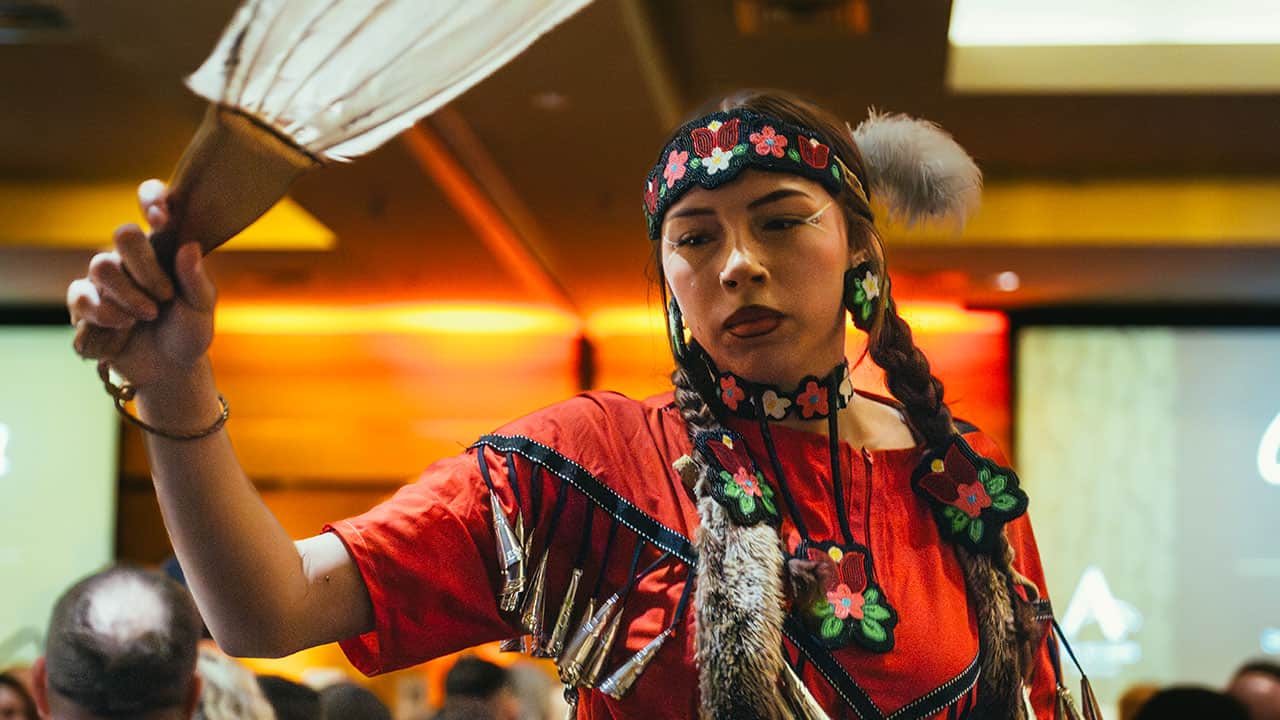 A student jingle dancer in traditional regalia performing.