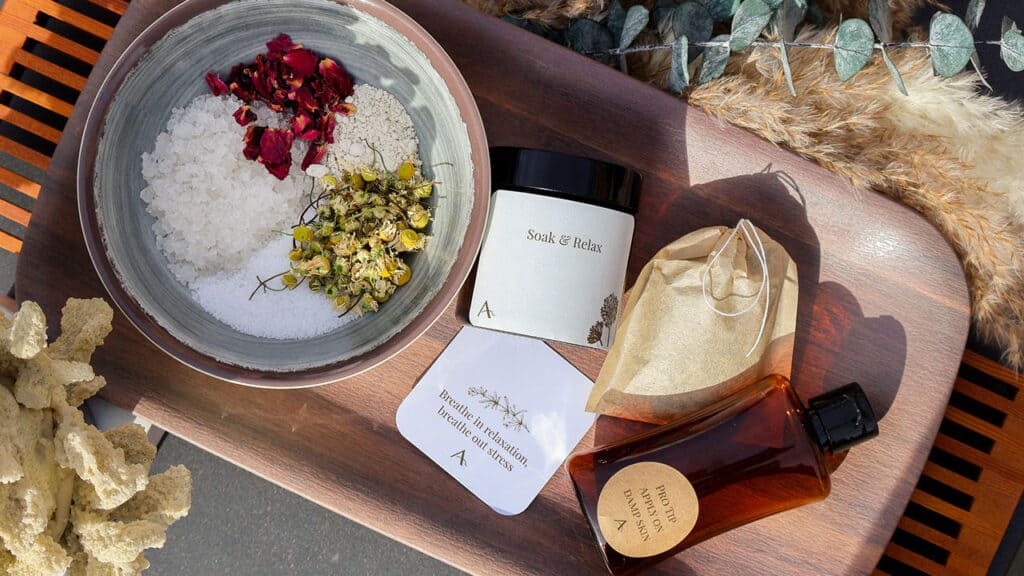 Dried herbs and salts in a boil with bottles for blending on a wooden tray.