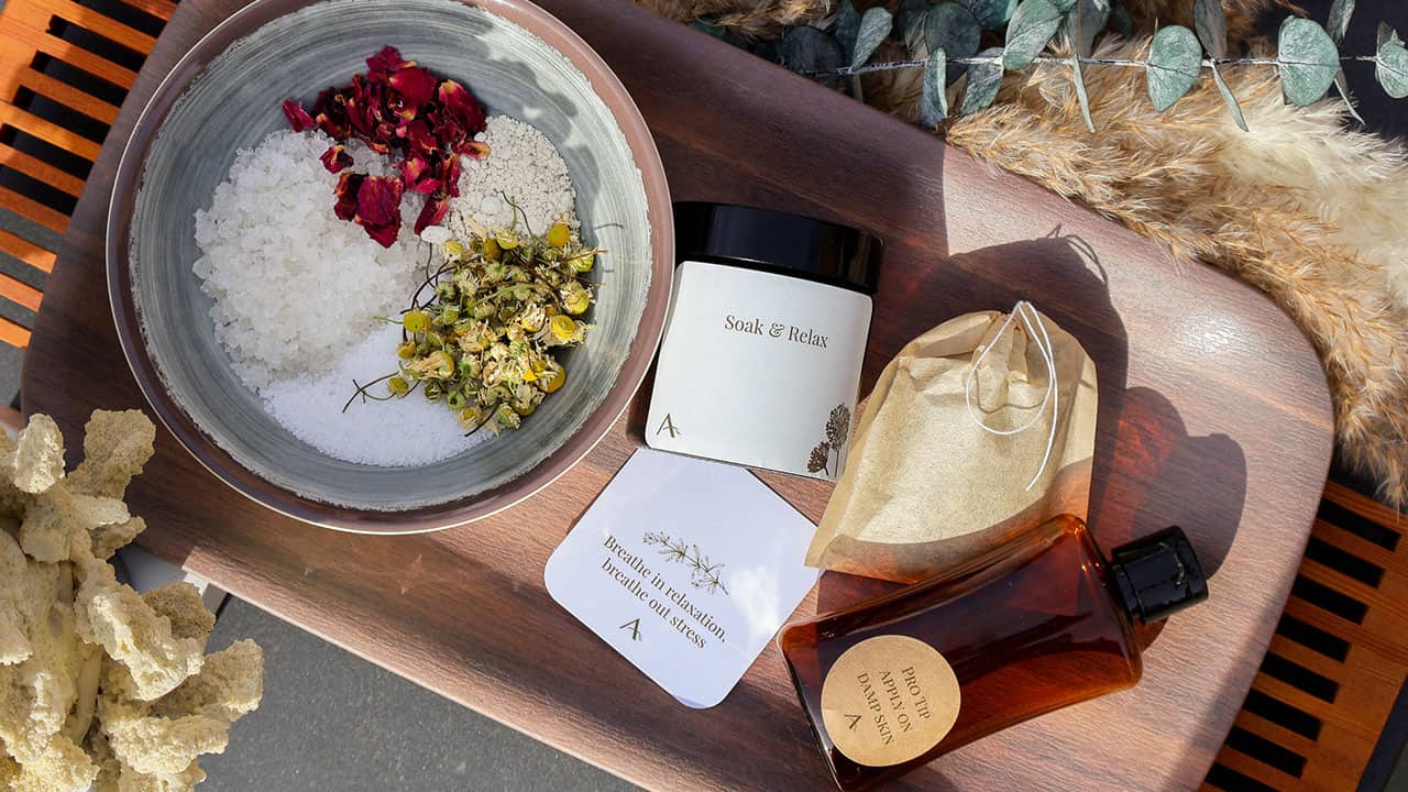 Dried herbs and salts in a boil with bottles for blending on a wooden tray.