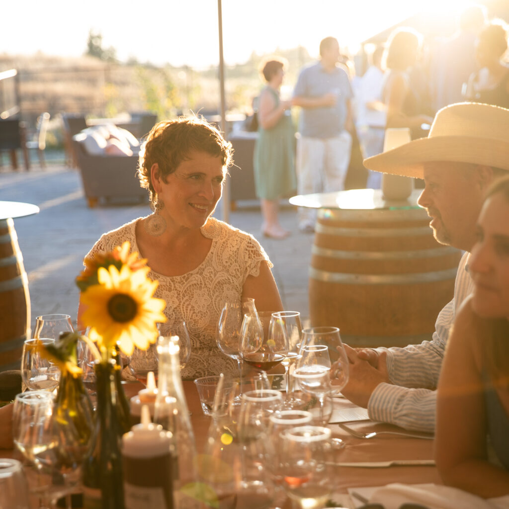 Clare Carver and Brian Marcy of Big Table Farm seated with guests at a dinner event.