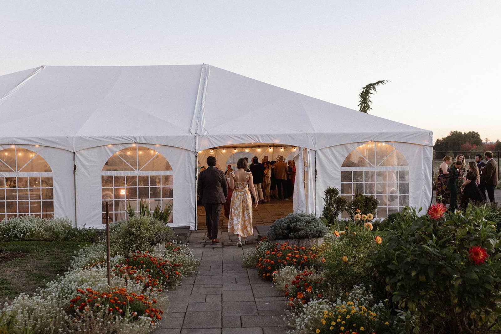 Two guests entering the dinner tent in the Chef's Garden for an evening event.
