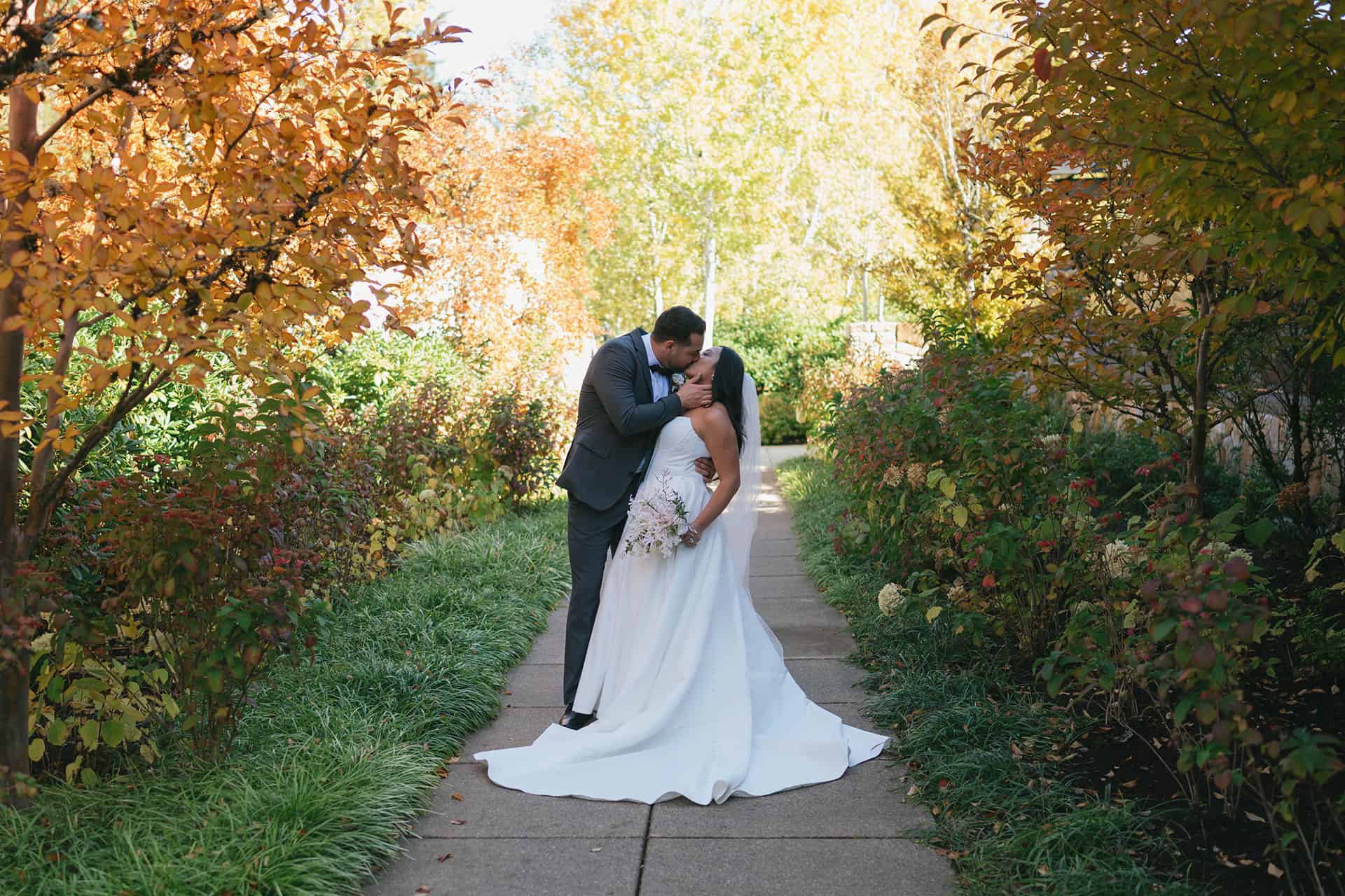 A bride and groom stealing a kiss among the golden autumn leaves at The Allison Inn & Spa.