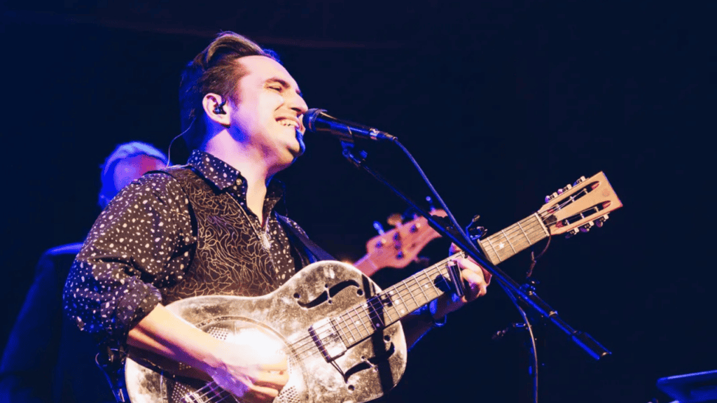 Musician Ben Rice singing with his guitar.