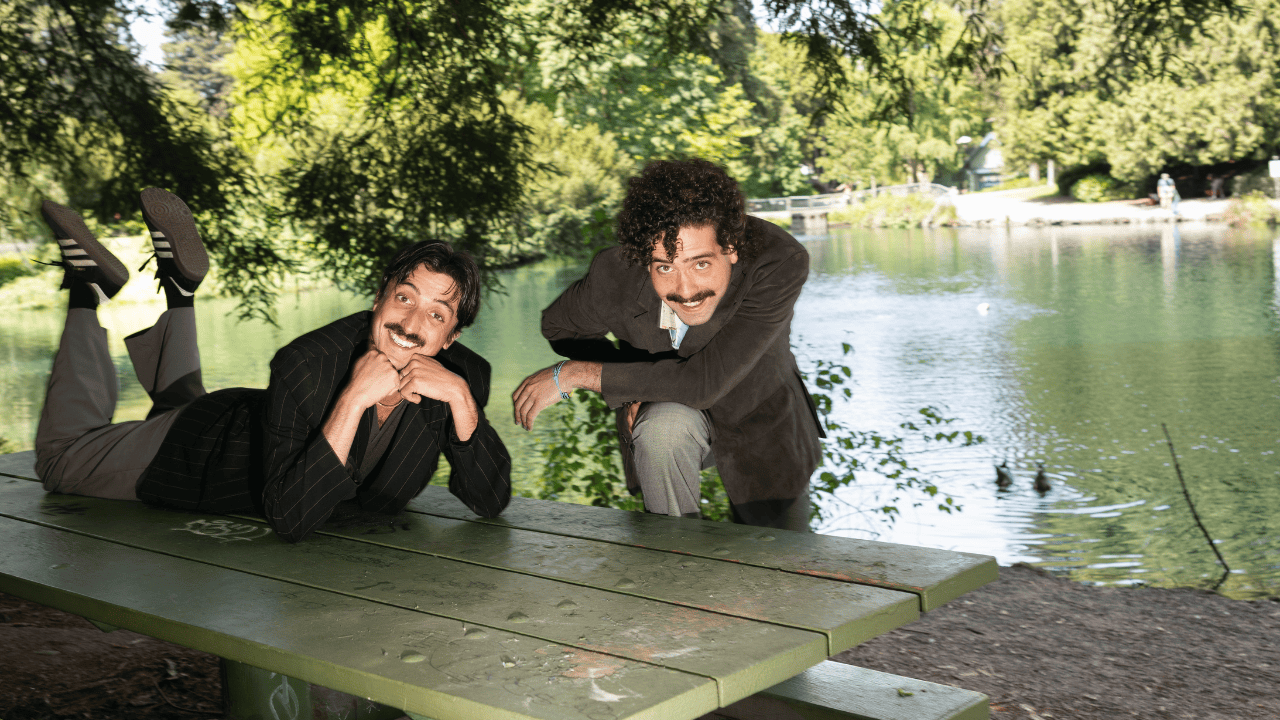 A picture of Johnny Franco & His Real Brother Dom on a picnic table in front of a lake.