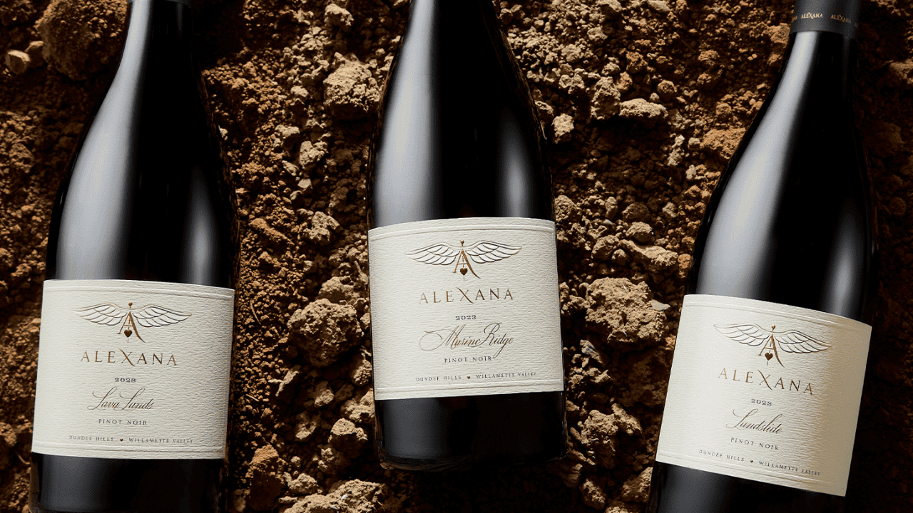 Three bottles of wine from Alexana Winery on soil.