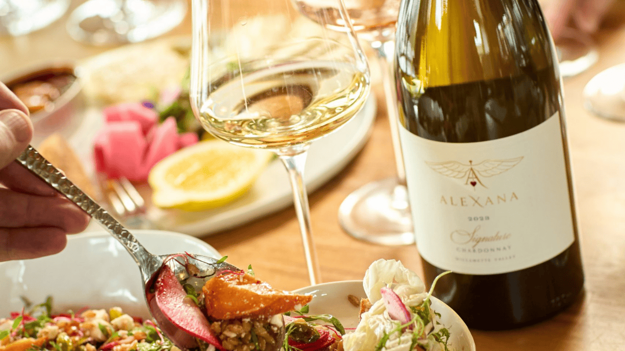 A bottle of wine from Alexana Winery with a glass and food.