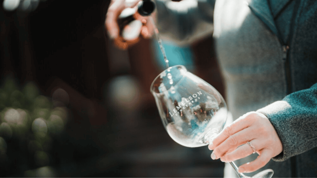 A bottle of wine poured into a glass with Lemelson Vineyard written on it.