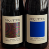 Two bottles of Sequitur Wine on a wood table.