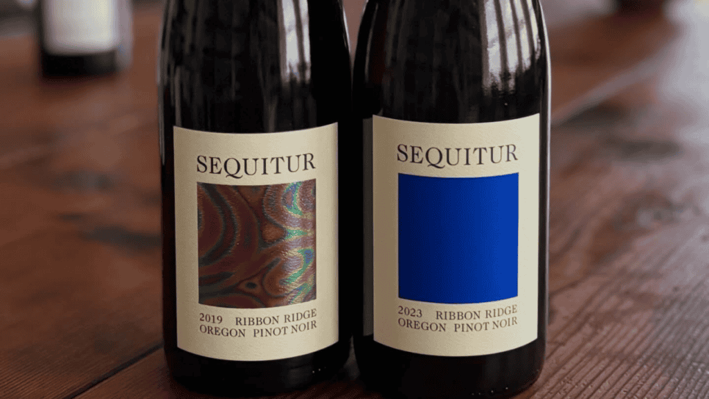 Two bottles of Sequitur Wine on a wood table.