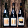 Three bottles of Sequitur Wine set amongst the trees.