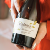 Two hands holding a bottle of Winderlea wine.